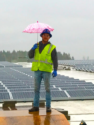 Solar Panel Installation with a construction manager holding and umbrella on a rainy day.
